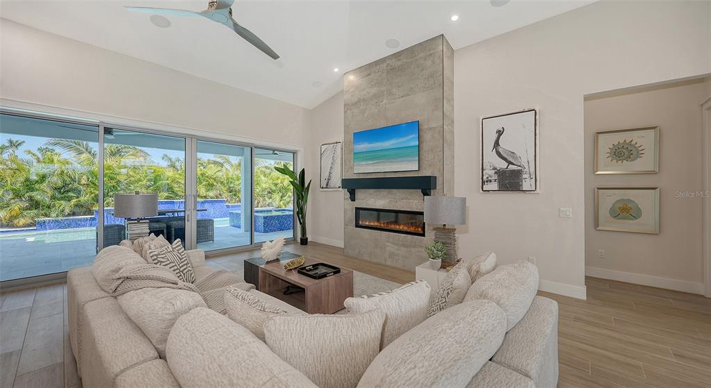 A living room features a stone fireplace, a large sectional sofa, and sliding glass doors — 8009 20TH PLACE W, BRADENTON, FL