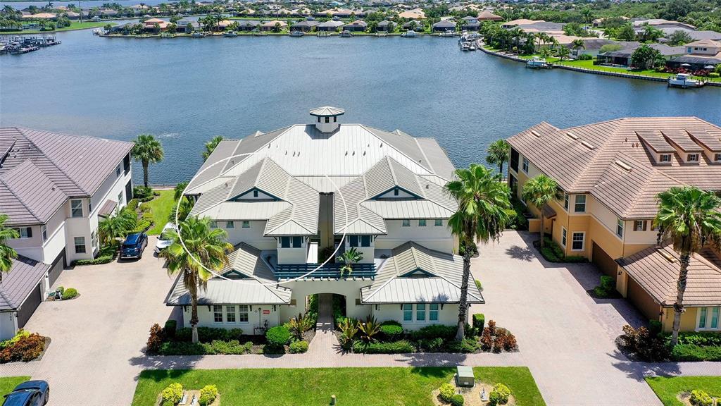 An aerial view shows a residential street with houses lining a lake and marina — 1041 RIVERSCAPE STREET UNIT 1041, BRADENTON, FL