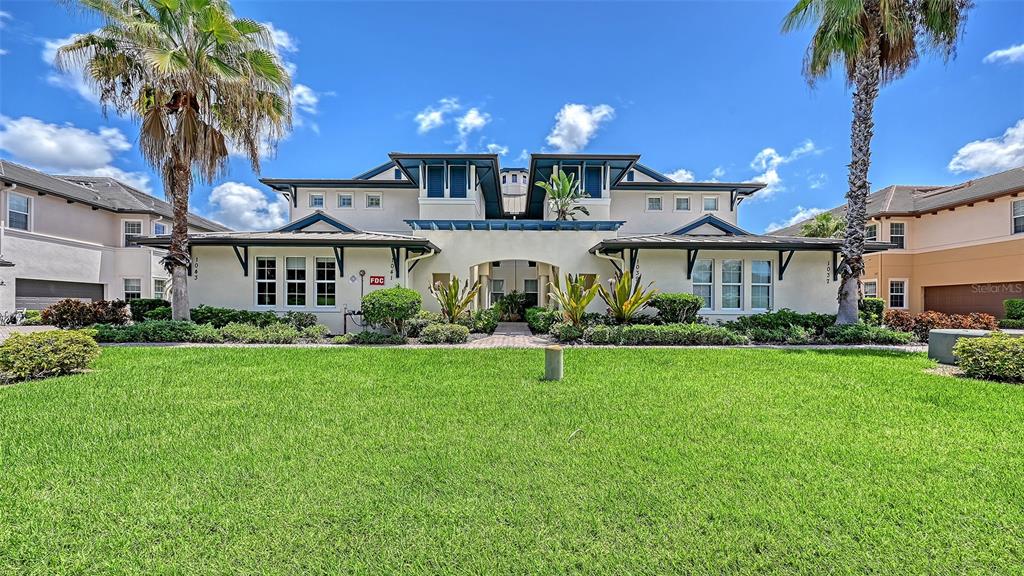 A multi-story residential building with a large front lawn and two prominent palm trees — 1041 RIVERSCAPE STREET UNIT 1041, BRADENTON, FL