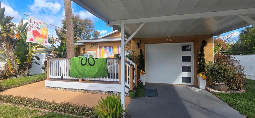 The exterior of a house features a covered carport, a front deck, and a garage — 1506 E 28TH AVENUE, TAMPA, FL