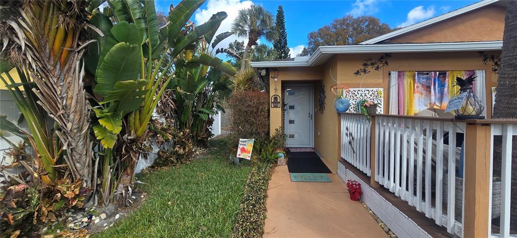 A walkway leads to the front door of a house with a wooden deck railing — 1506 E 28TH AVENUE, TAMPA, FL
