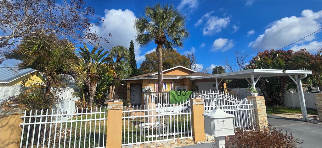 A single-story house with a white fence, a palm tree, and a carport — 1506 E 28TH AVENUE, TAMPA, FL
