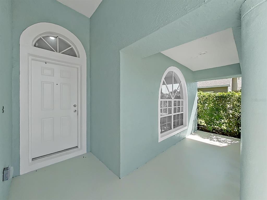 A covered entryway features a white front door, an arched window, and light blue walls — 1423 LAKE SHORE RANCH DRIVE, SEFFNER, FL