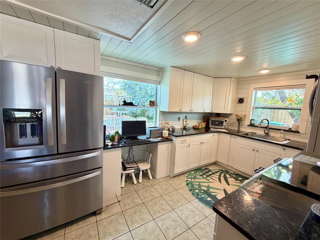 A kitchen features white cabinets, stainless steel appliances, a desk area, and tile flooring — 7004 ROCKWOOD DR, PORT RICHEY, FL