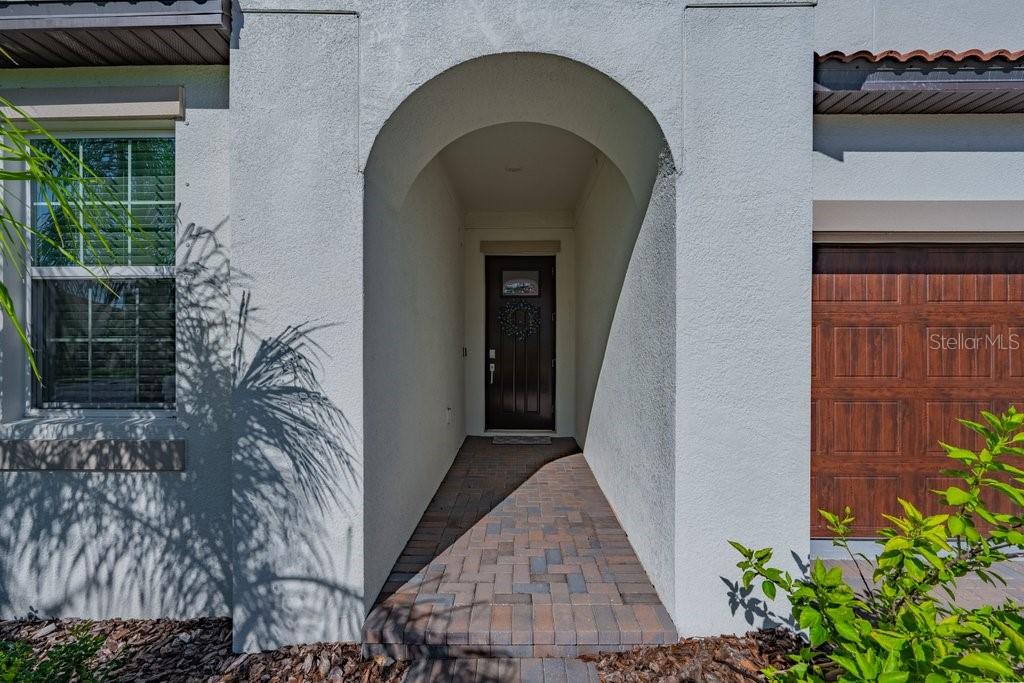 A paved walkway leads to a recessed front door under an arched entryway — 17253 STAR BANKS STREET, WIMAUMA, FL