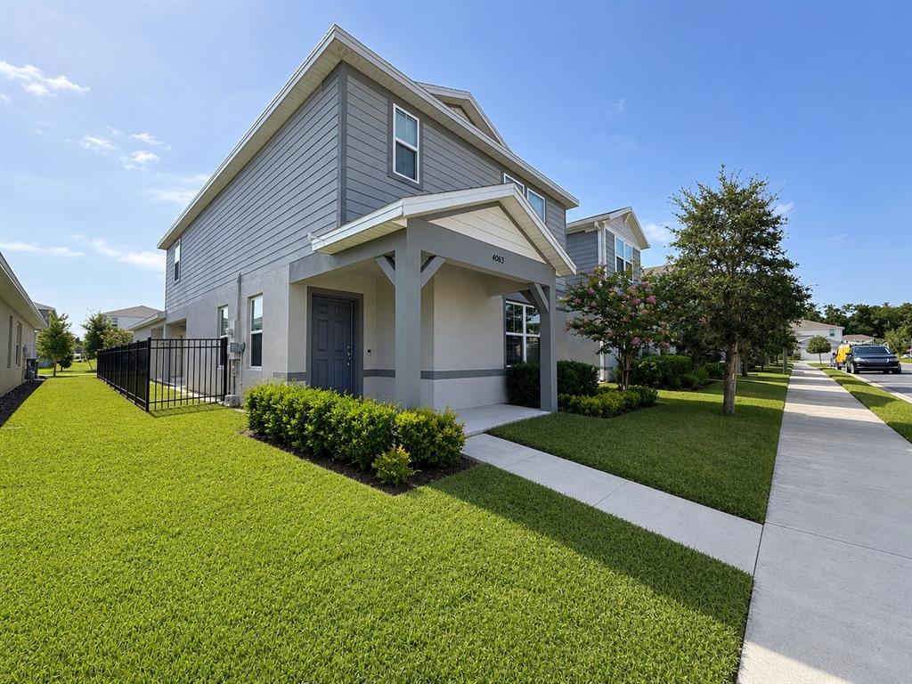 A two-story gray house with a covered porch and a black metal fence — 4083 FEATHER TREE DRIVE, APOPKA, FL
