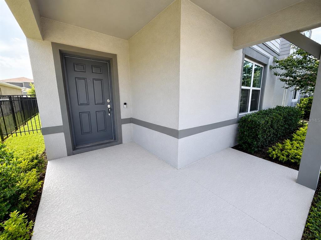 A covered concrete entryway features a dark gray front door and a single window — 4083 FEATHER TREE DRIVE, APOPKA, FL