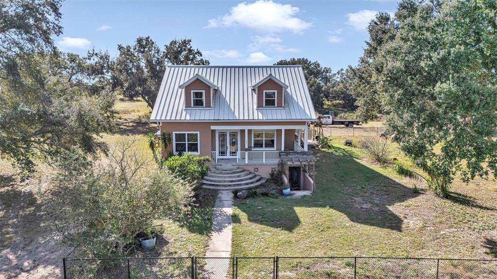A two-story house with a metal roof and a curved concrete staircase sits on land — 13800 COUNTY ROAD 450, UMATILLA, FL