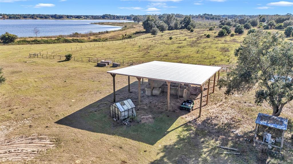 An aerial view shows a large metal-roofed pole barn with hay bales and a greenhouse — 13800 COUNTY ROAD 450, UMATILLA, FL