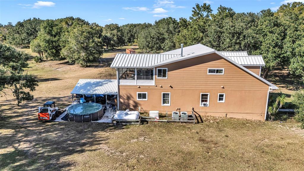 An aerial view shows a two-story tan house with a metal roof and a pool — 13800 COUNTY ROAD 450, UMATILLA, FL