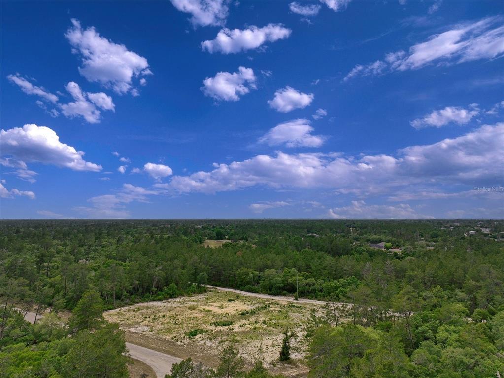 An aerial view shows a cleared, sandy lot surrounded by dense green forest and trees — SW 35TH TERRACE, OCALA, FL