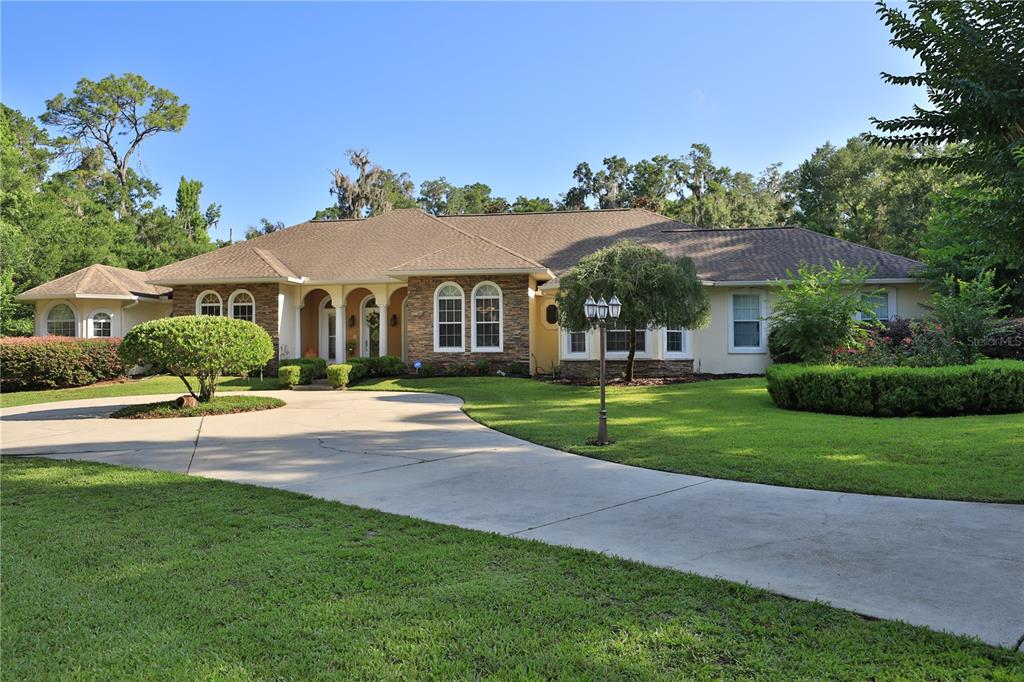 A single-story house with a stone facade, arched entryway, and a circular concrete driveway — 1351 SE 91ST PLACE, OCALA, FL