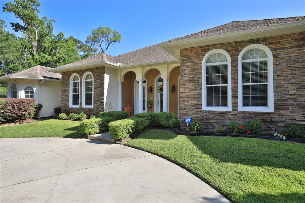 A single-story house with a stone facade, arched windows, and a concrete driveway — 1351 SE 91ST PLACE, OCALA, FL