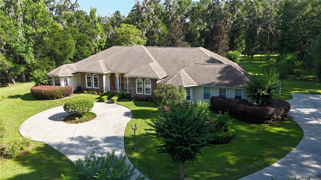 An aerial view of a single-story house with a circular driveway and surrounding trees — 1351 SE 91ST PLACE, OCALA, FL