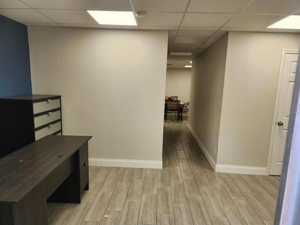 An office space features a dark desk, wood-look tile flooring, and a doorway leading to another room — 1223 COLUMBIA STREET, ORLANDO, FL