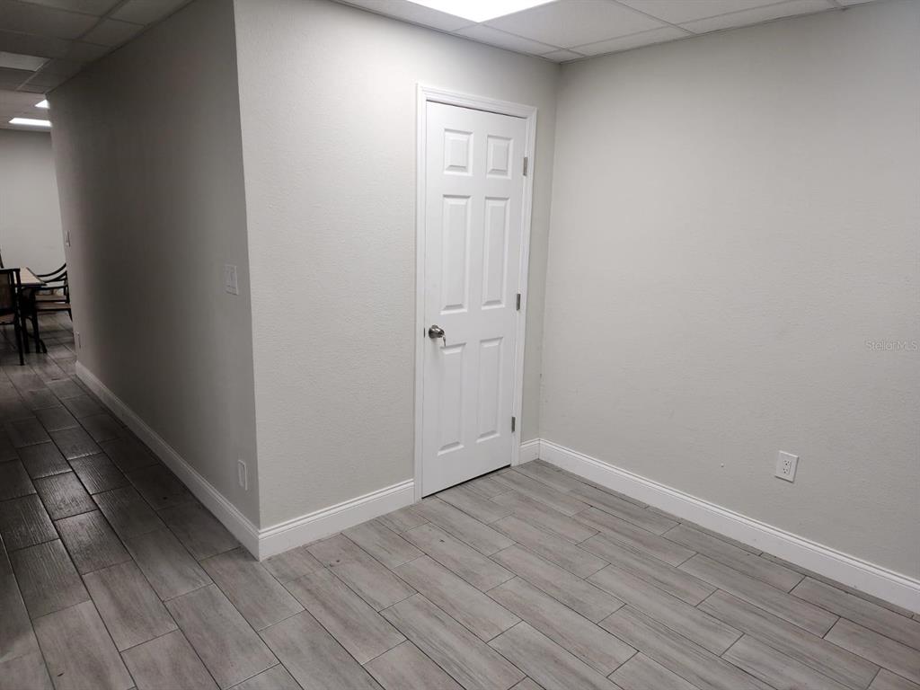 A room with light gray walls, wood-look tile flooring, and a white six-panel door — 1223 COLUMBIA STREET, ORLANDO, FL