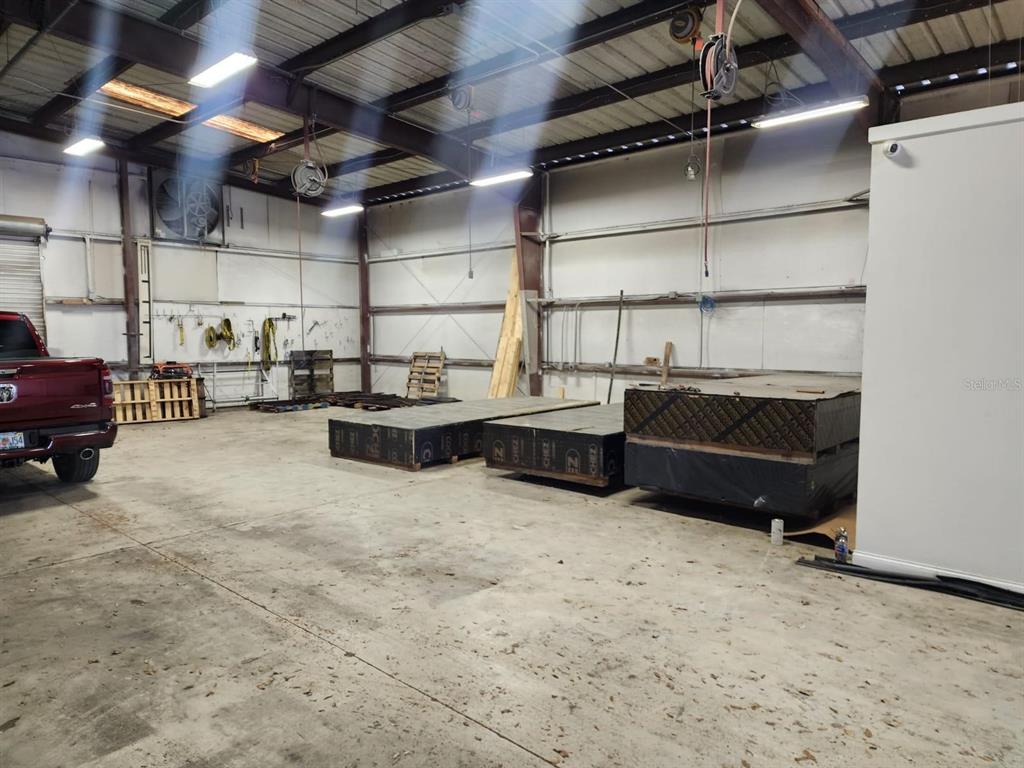 A large industrial warehouse space features concrete floors, exposed metal beams, and stacked plywood pallets — 1223 COLUMBIA STREET, ORLANDO, FL