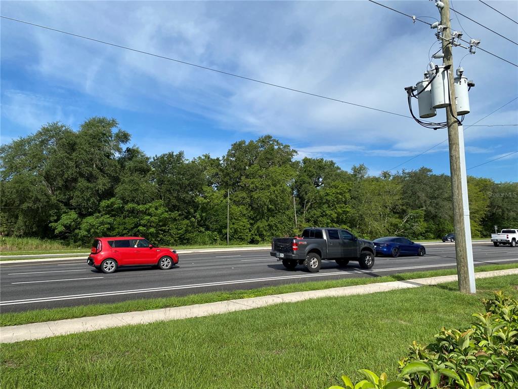 A view of a multi-lane road with cars passing by a wooded area and utility pole — 524 S HIGHWAY 27/441, LADY LAKE, FL