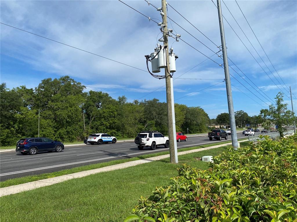 A utility pole stands beside a multi-lane road with several vehicles driving past — 524 S HIGHWAY 27/441, LADY LAKE, FL