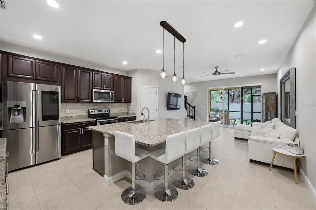 A living room features a white sectional sofa, a large wall mirror, and sliding glass doors — 2013 SUNSET WIND LOOP, OLDSMAR, FL
