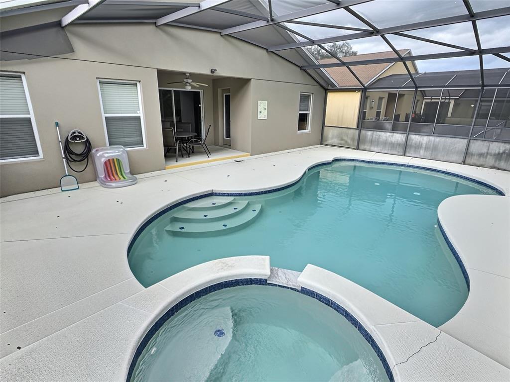 A screened-in patio features a swimming pool, an attached spa, and a concrete deck — 655 SCRUB JAY WAY, DAVENPORT, FL