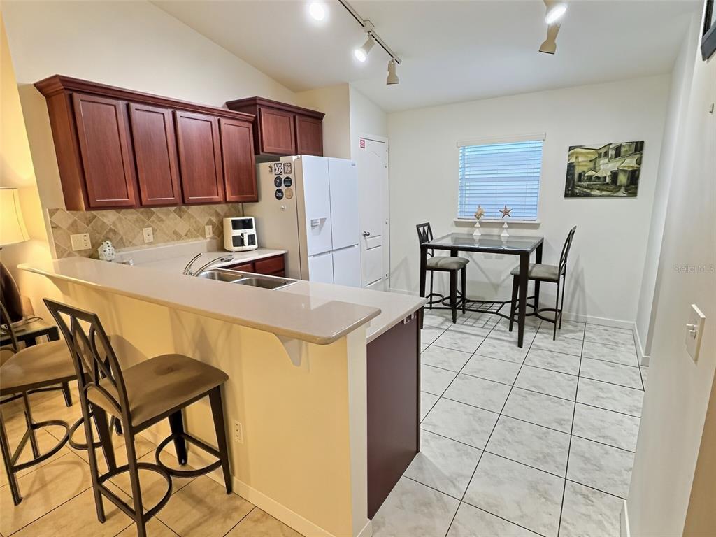 A kitchen with dark wood cabinets, a breakfast bar, and a dining area with tile floors — 655 SCRUB JAY WAY, DAVENPORT, FL