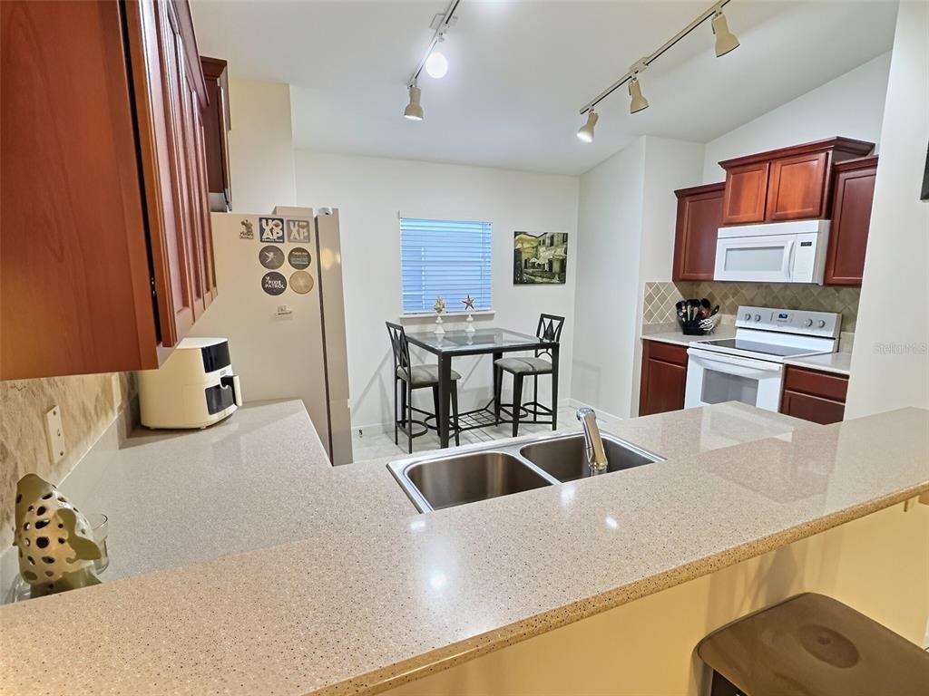 A kitchen with wood cabinets, quartz countertops, a double sink, and a small dining area — 655 SCRUB JAY WAY, DAVENPORT, FL