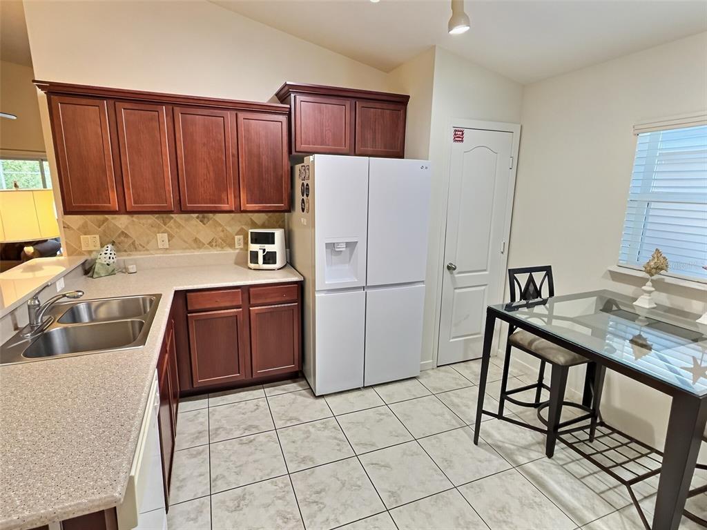 A kitchen features dark wood cabinets, a white refrigerator, a double sink, and a dining table — 655 SCRUB JAY WAY, DAVENPORT, FL
