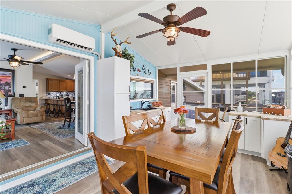 A sunroom features a wooden dining table, ceiling fan, and a view into the kitchen — 11639 W CLEARWATER COURT, HOMOSASSA, FL