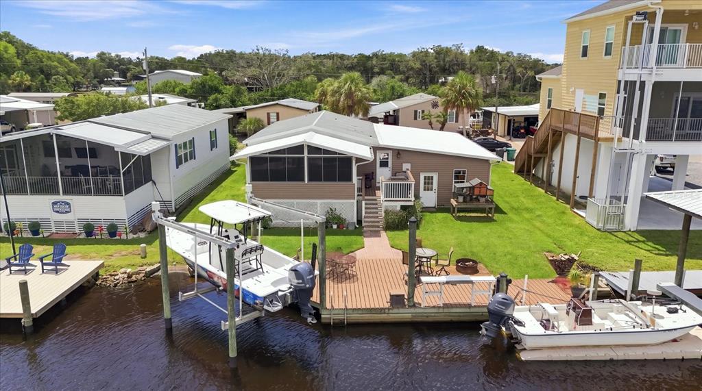 An aerial view shows a waterfront house with a boat lift, dock, and grassy yard — 11639 W CLEARWATER COURT, HOMOSASSA, FL