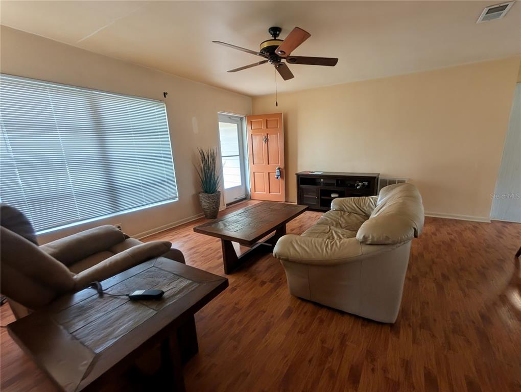 A living room features wood-look flooring, a ceiling fan, a sofa, and a coffee table — 969 6TH AVENUE NE, LARGO, FL
