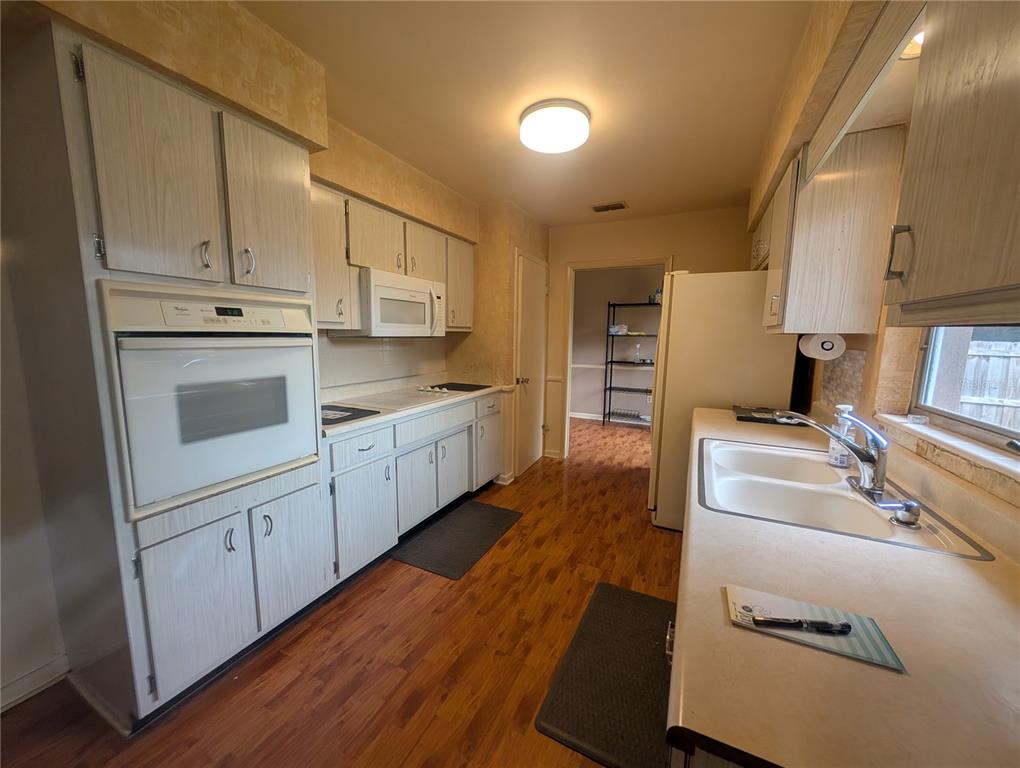 A kitchen features light wood cabinets, white appliances, a double sink, and wood-look flooring — 969 6TH AVENUE NE, LARGO, FL
