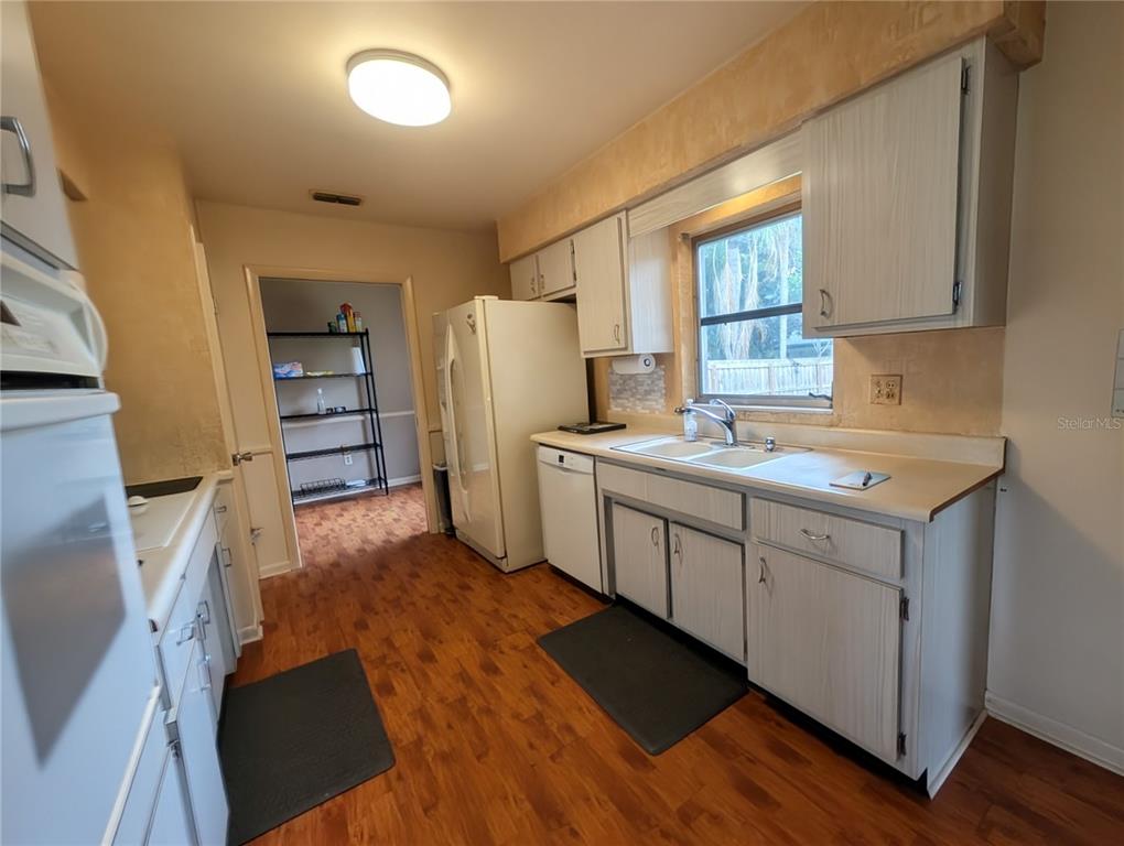 A kitchen features light-colored cabinets, wood-look flooring, a white refrigerator, and a window above the sink — 969 6TH AVENUE NE, LARGO, FL