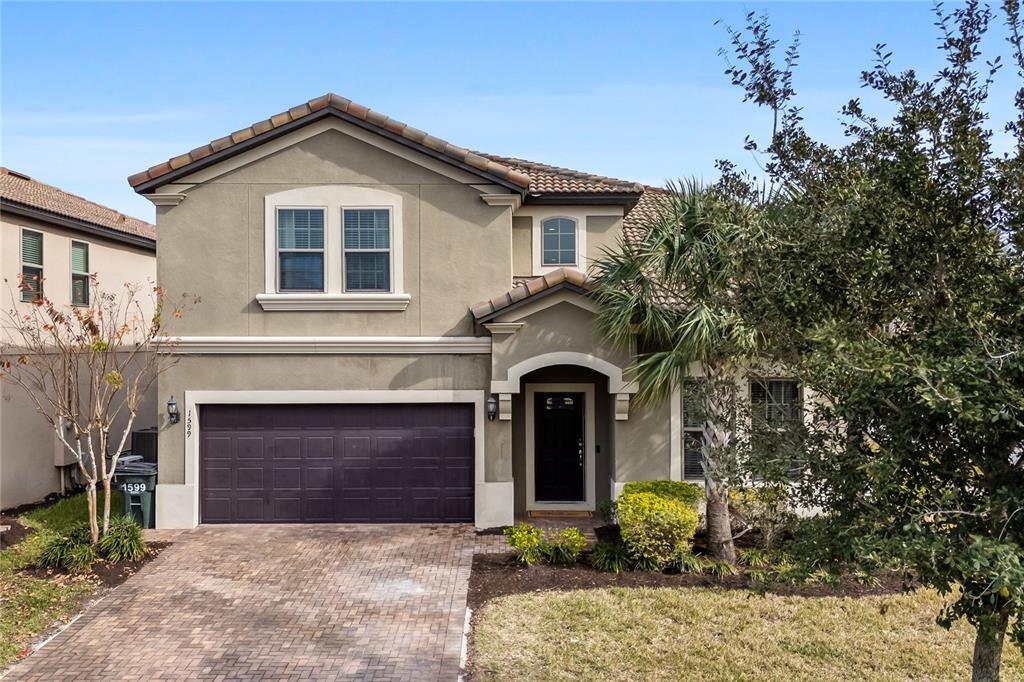 A two-story house with a brown garage door, tan stucco exterior, and a paved driveway — 1599 LIMA AVENUE, KISSIMMEE, FL