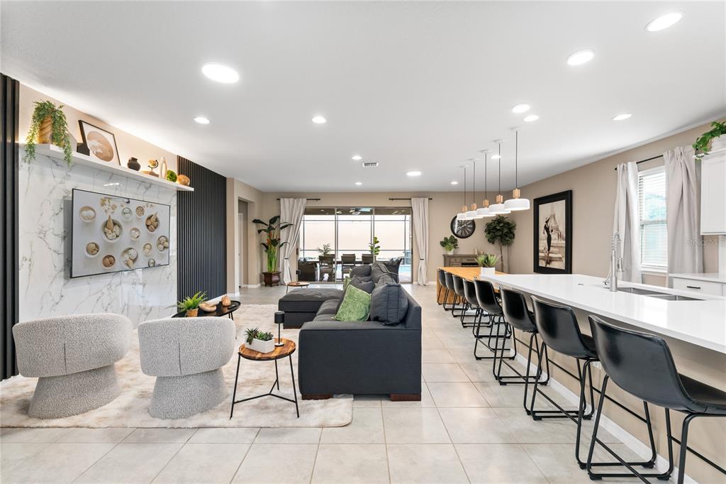 An open-concept living room and kitchen area features a marble fireplace wall and island seating — 1599 LIMA AVENUE, KISSIMMEE, FL