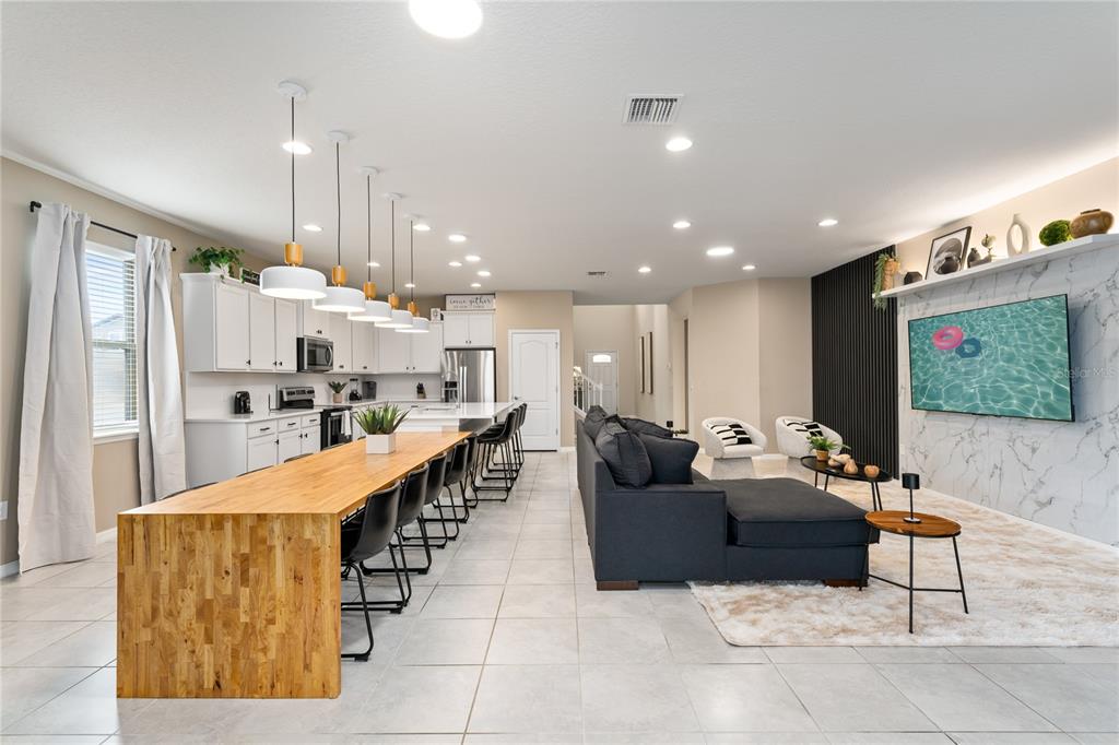 An open-concept kitchen and living area featuring a long wooden island and marble-accented wall — 1599 LIMA AVENUE, KISSIMMEE, FL