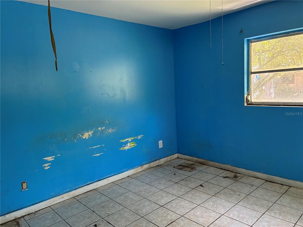 A room with blue walls, damaged paint, and light-colored floor tiles — 17990 SE 51ST STREET, OCKLAWAHA, FL