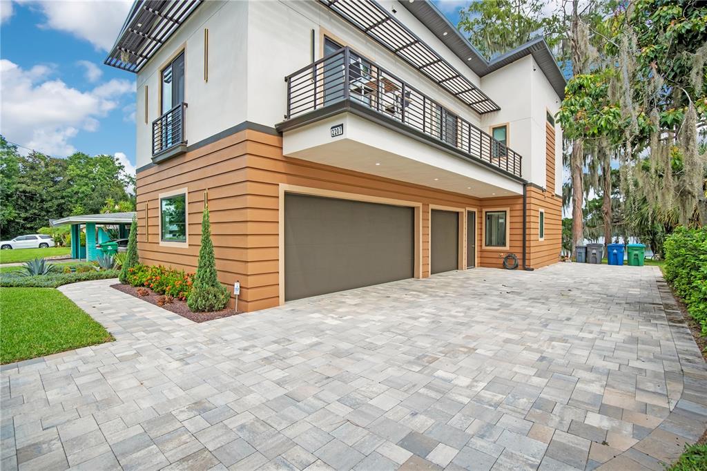 A grassy backyard with a concrete patio, tall trees, and a wooden dock on a lake — 2207 KINDEL AVENUE, WINTER PARK, FL
