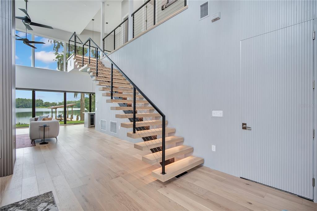 A modern kitchen features a large gray island, white countertops, and floor-to-ceiling windows overlooking a lake — 2207 KINDEL AVENUE, WINTER PARK, FL