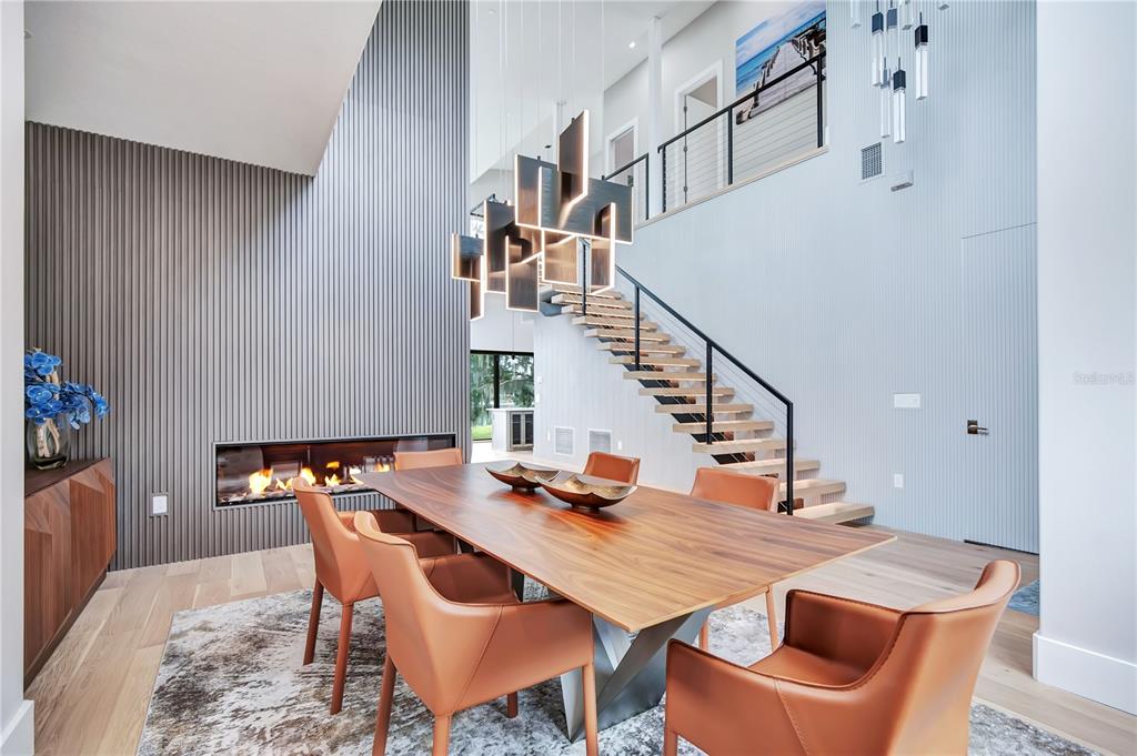 A modern living room with floor-to-ceiling windows, a floating staircase, and a view of a lake — 2207 KINDEL AVENUE, WINTER PARK, FL