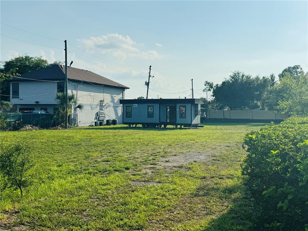 A small, rectangular, grey portable building sits on a grassy lot next to a house — 8390 S US HIGHWAY 17-92 HIGHWAY UNIT 1001-1009, FERN PARK, FL