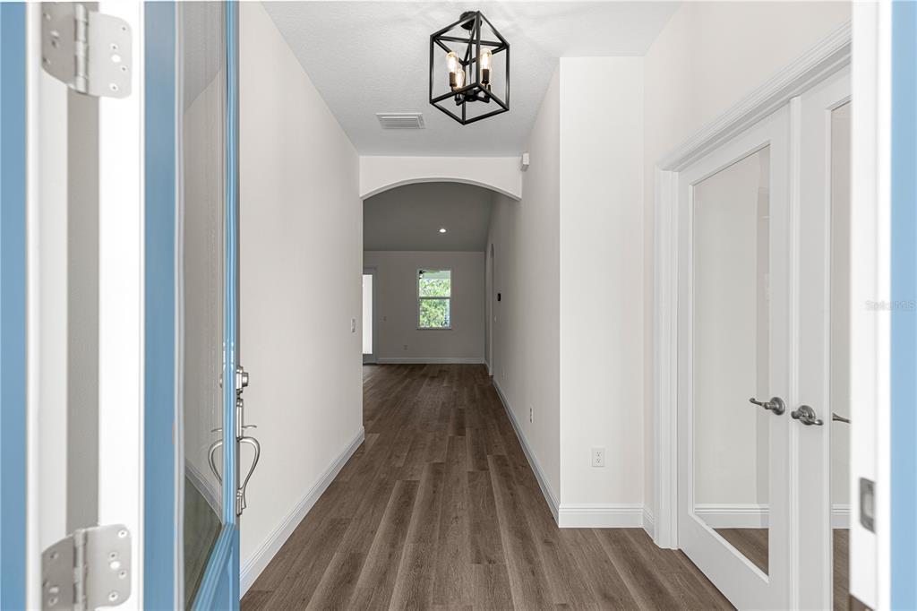 A bright entryway features wood-look flooring, a geometric pendant light, and white French doors — 12359 SW 88 STREET, DUNNELLON, FL