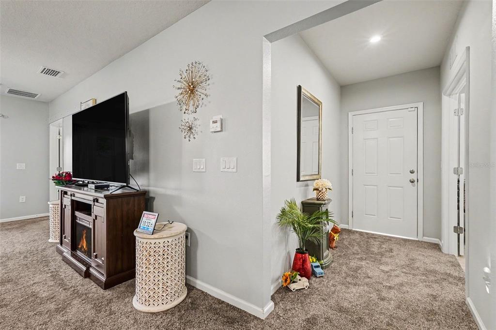 A living area with a television console and an entryway featuring a white door — 17745 TURNING LEAF CIRCLE, LAND O LAKES, FL