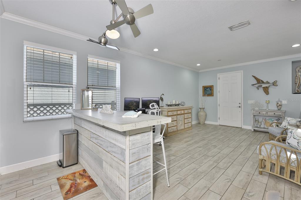 An open-concept living room and kitchen featuring a grey sectional, island seating, and tile flooring — 5227 ADMIRAL POINTE DRIVE, APOLLO BEACH, FL