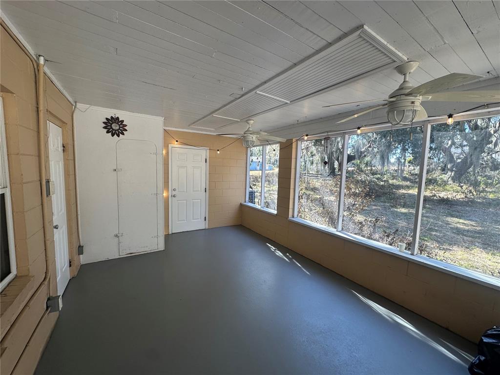 A screened-in porch with a gray floor, white walls, ceiling fans, and large windows — 5520 OHIO AVENUE, LADY LAKE, FL