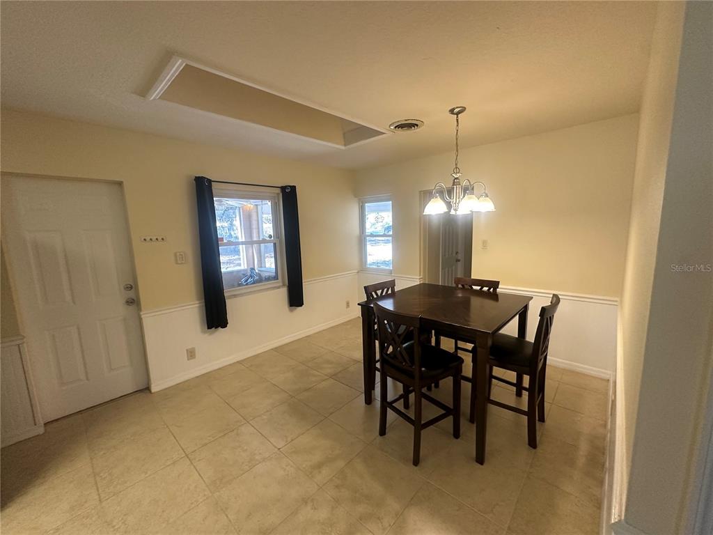 A dining room features tile flooring, a wooden table with chairs, and a chandelier — 5520 OHIO AVENUE, LADY LAKE, FL