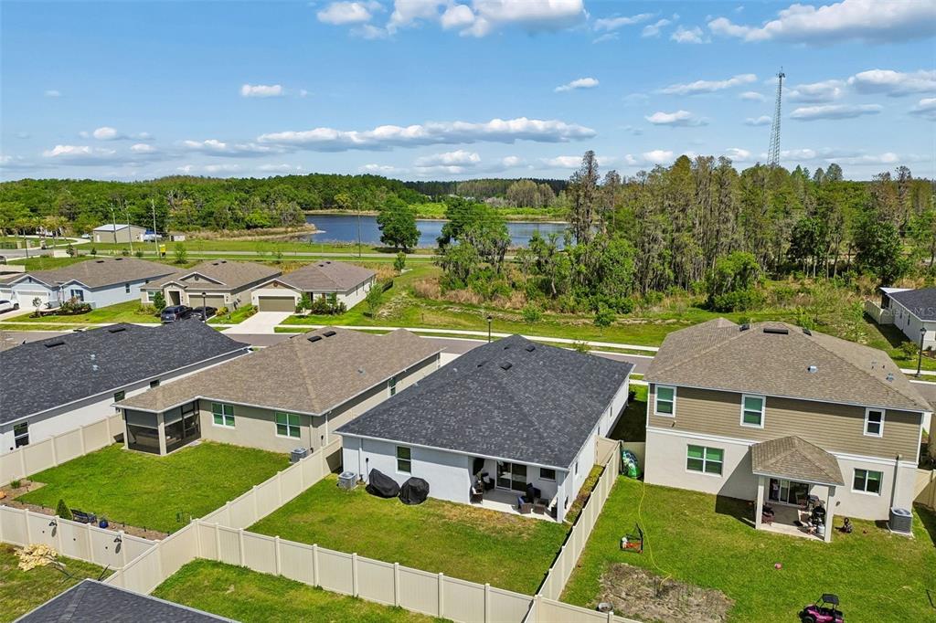 An aerial view of suburban houses with fenced backyards and a lake in the distance — 20121 AZUL MARBLE LOOP, LAND O LAKES, FL