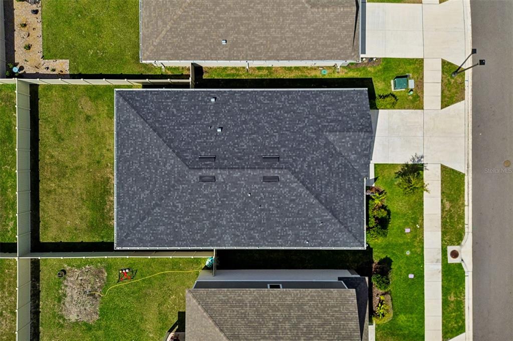 An aerial view shows the dark shingled roof of a house surrounded by green lawns — 20121 AZUL MARBLE LOOP, LAND O LAKES, FL
