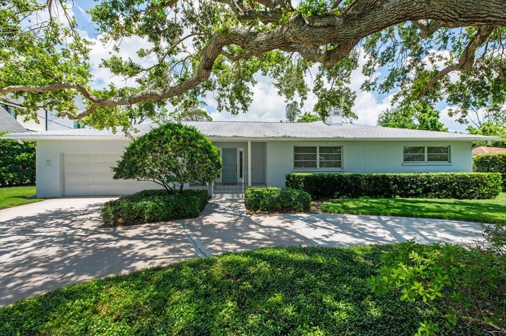 A single-story light blue house with a two-car garage and a large oak tree — 1541 FLOWER DRIVE, SARASOTA, FL
