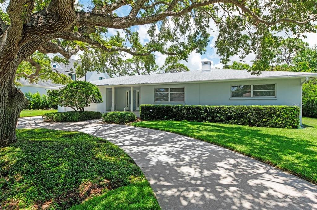 A single-story house with a light-colored exterior, a concrete driveway, and a large oak tree — 1541 FLOWER DRIVE, SARASOTA, FL